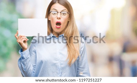 Young beautiful business woman holding blank card over isolated background scared in shock with a surprise face, afraid and excited with fear expression