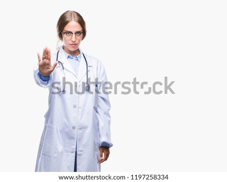 Beautiful young blonde doctor woman wearing medical uniform over isolated background doing stop sing with palm of the hand. Warning expression with negative and serious gesture on the face.