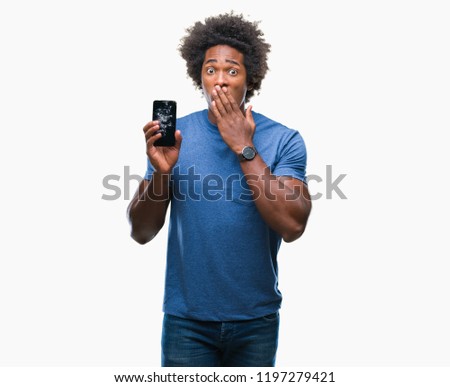 Afro american man holding broken smartphone over isolated background cover mouth with hand shocked with shame for mistake, expression of fear, scared in silence, secret concept