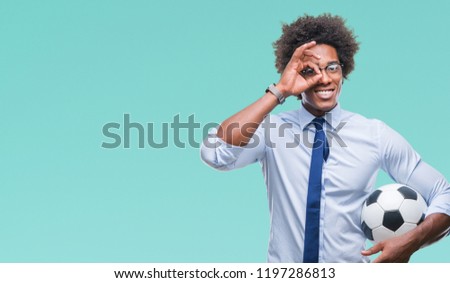 Afro american manager man holding soccer ball over isolated background with happy face smiling doing ok sign with hand on eye looking through fingers