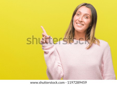 Young beautiful woman wearing winter sweater over isolated background with a big smile on face, pointing with hand and finger to the side looking at the camera.