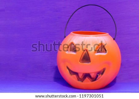 Happy Halloween with a fun and bright pumpkin. Purple background for Halloween cards. Trick or treat. Smiling pumpkin for banners and templates