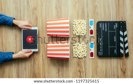 Man watching movies streaming online using a digital tablet, popcorn, 3D glasses and clapboard, cinema and entertainment concept