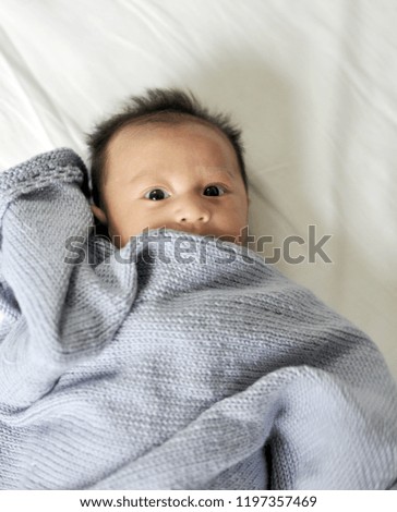 Cute happy baby new born lying on a blue knitted blanket. Funny little baby 