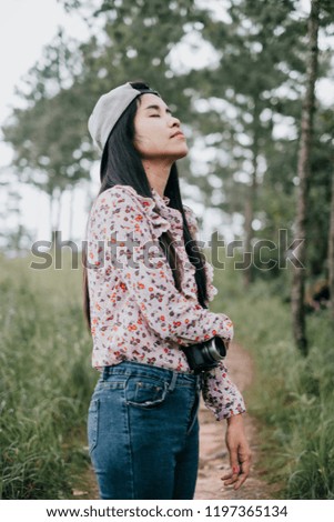 Woman photography standing in forrest with tripod and camera.