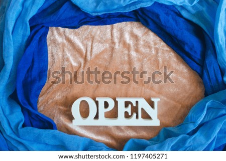 Open sign word is wood desk sign on blue woven fabric background.