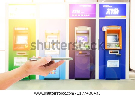 Man use mobile phone, blur image of the ATM as background. 