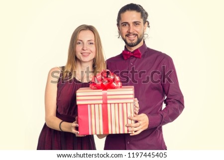 Loving couple with a gift in their hands on light background. Christmas, New Year, Valentine day, holiday gift - concept.