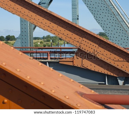 orange painted steel structure of a bridge with bolts and nuts