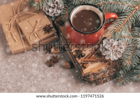 Bright red cup of hot cocoa on wooden cutting board with Christmas decorations and snow effect. Top view. Copy space