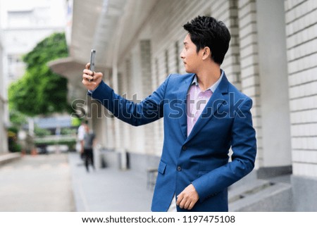 Business Concept - Portrait Handsome Business man take a selfie of himself with smartphone on urban