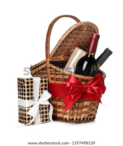 Festive basket with bottles of wine and gifts on white background