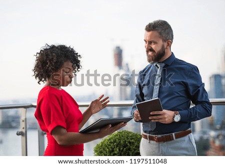 A portrait of two businesspeople standing against London view panorama.