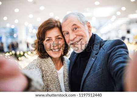 Senior couple taking selfie in shopping center at Christmas time.
