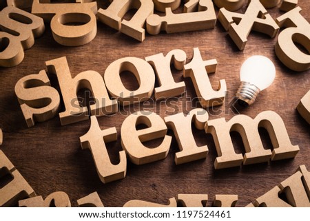 Short Term word in scattered wood letters with glowing white light bulb Royalty-Free Stock Photo #1197524461