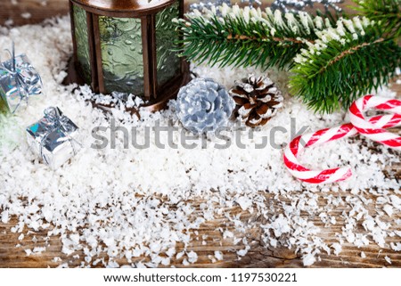 Christmas lantern, fir branch and candy in the snow. Christmas decor.