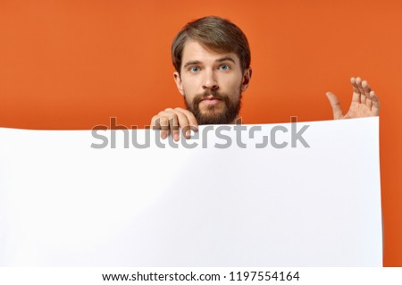 man holds in his hand a mock-up on an orange background                       