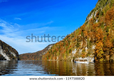 The most clear lake in Germany. The lake in Bavarian Alps. The view of Bavarian Alps from the lake. Autumn landscape. Autumn mountains and rocks in Germany. Autumn trees on the lake coast.