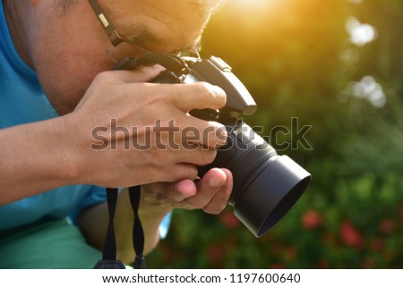 Senior 45-55 year old holding camera and take photo at publish park,Photographer activity