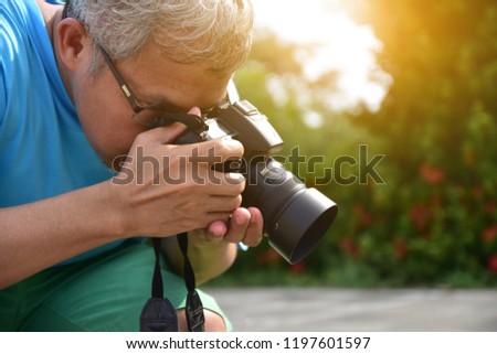 Senior 45-55 year old holding camera and take photo at publish park,Photographer activity