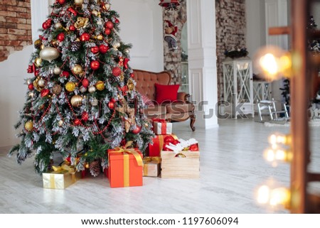 Christmas and New Year decorated interior room with red presents and New year tree and classic brown sofa in front of white wall.