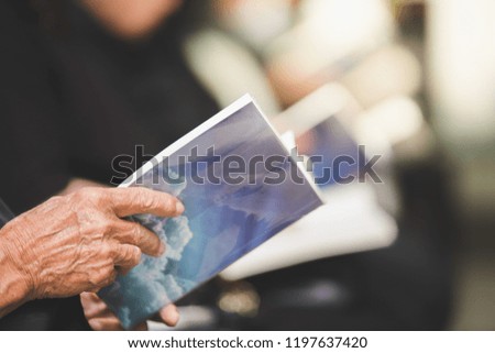 Selective focus of old man holding a prayer book in the church