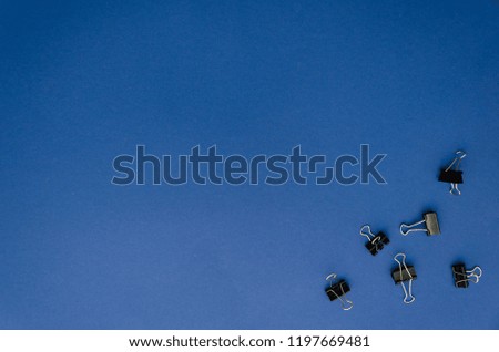 Binder clips in the down-right corner of a blue background