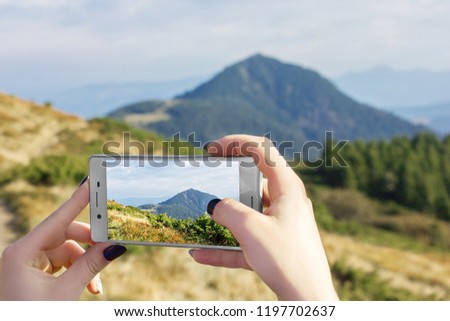 A girl photographs on the phone a beautiful mountain landscape.