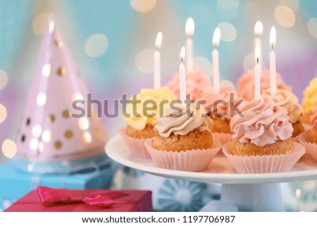 Stand with delicious birthday cupcakes on table
