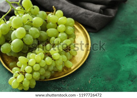 Metal tray with ripe juicy grapes on color table