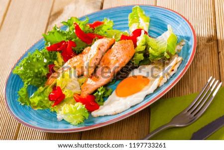 Picture of tasty breakfast with  trout, egg, pepper and lettuce at plate on table