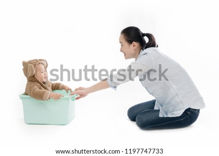 The baby was sitting in the box playing with his mother