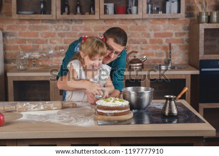 Little girl with her father decorate cake