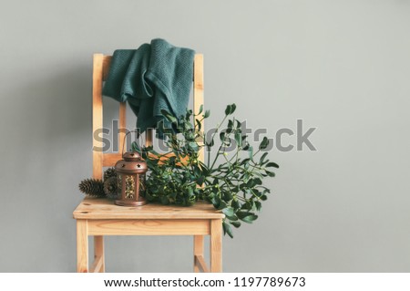 Lantern, cones and mistletoe bunch on a simple vintage wooden chair, home decorating for Christmas concept