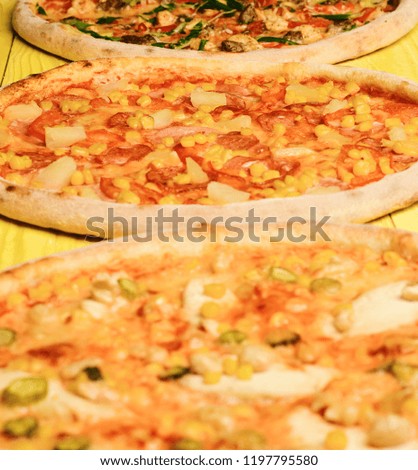Hawaii pizza with meat, corn, tomatoes and cheese on yellow wood background. Different pizza set for menu. Fast food restaurant concept. Take away food with various ingredients and crunchy edges