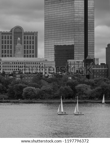 black and white of two sailboats racing on the charles river in boston with hancock tower (200 clarendon) and boston skyline in the background