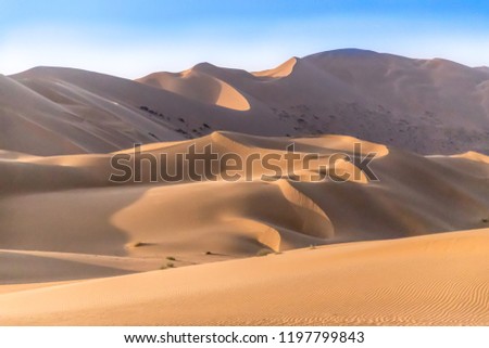 Badain Jaran  Desert in Inner Mongolia, China, the third  largest desert in China, with the tallest stationary dunes on Earth blue sky & white clouds in background Royalty-Free Stock Photo #1197799843