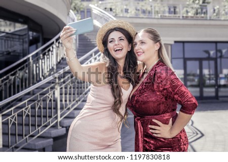 Happy sisters. Delighted happy women standing together while taking a selfie