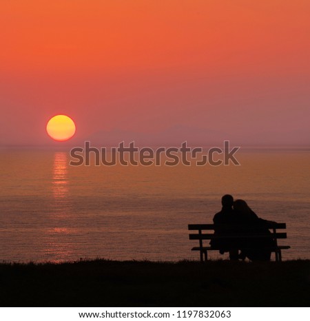 Couple sitting on park bench watching the sunset., the subject is blurry and not focused