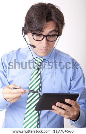 Portrait of a young receptionist talking with a headset holding tablet.