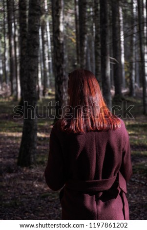 Girl with red hair walks in fairytale forest in beautiful light. Nordic lifestyle and outdoor activities in autumn season. Twilight zone with girl.
