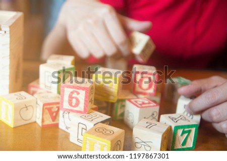 Unidentified people in red cloth playing character letters wooden block on table, relaxing concentrate brain training.