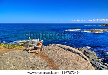 Beautiful landscape with wooden chair on rocky shore