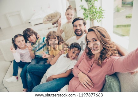 Mom makes selfie picture photo with big family for her blog, sit on white comfort, cozy sofa or couch in modern light interior apartment