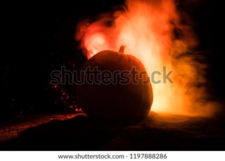 Halloween theme with pumpkin against smoky dark background. Empty space for text. Selective focus