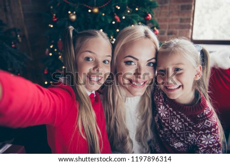 Christmastime december fairy eve winter noel festive. Cheerful funky funny face stylish blonde parent mama little small preteen in sweater take picture on front camera modern smartphone in cozy house