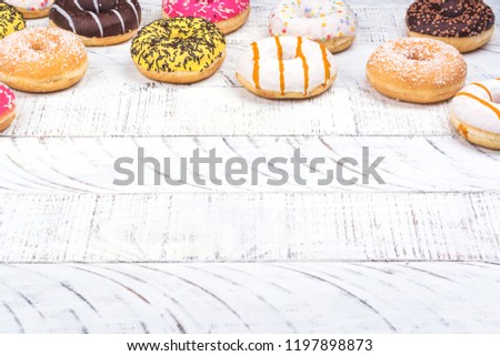 Rows of colorful donuts with sprinkles and different fillings on white background. Copy space