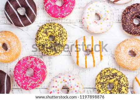 Rows of colorful donuts with sprinkles and different fillings on white background. Copy space