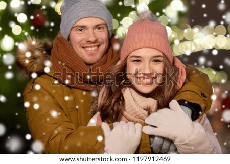 winter holidays and people concept - happy young couple dating and hugging at christmas tree in evening