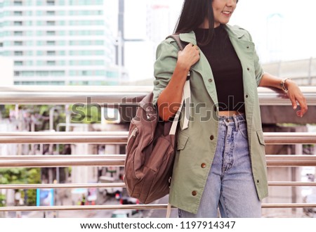 Beautiful woman smiling and holding bag for traveling in the Bangkok city.	